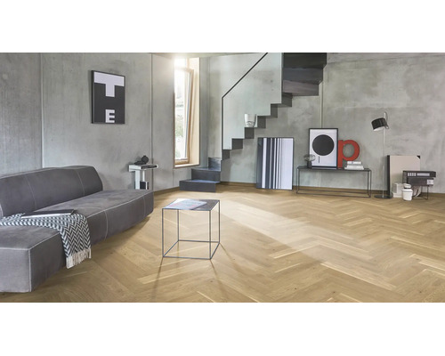Salon moderne avec parquet en chevrons en bois de chêne, murs en béton apparent gris et escalier au design minimaliste.