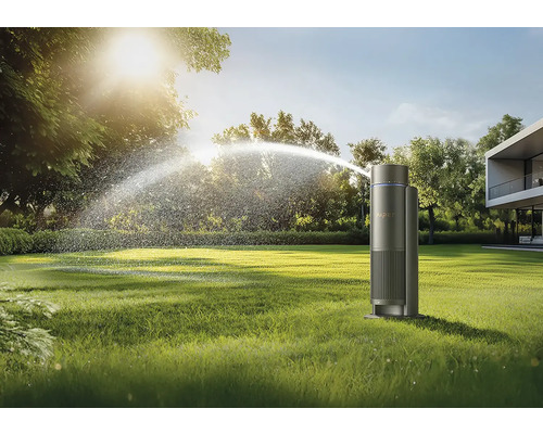 Rasensprenger beim Bewässern eines Gartens vor einem modernen Haus.