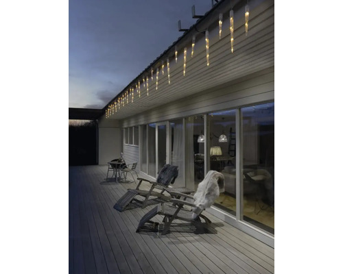 Façade de maison avec guirlande lumineuse glaçons, chaises longues et terrasse pour une ambiance chaleureuse