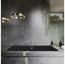 Salle de bains avec baignoire noire, plafonniers ronds et mur en béton