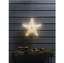 Dekorativer beleuchteter Stern hängt vor einer Holzpaneelwand, darunter ein Tisch mit Moos, Äpfeln und einer Schriftrolle.