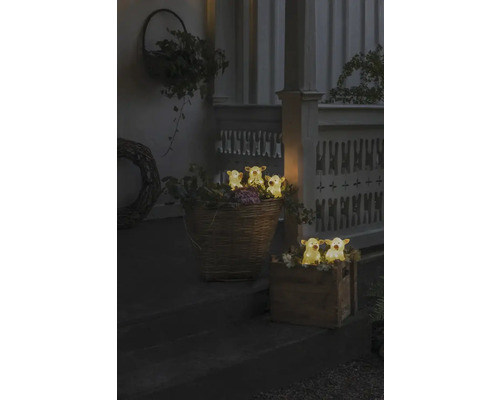 Dekorative Szene mit beleuchteten Kuhfiguren in Körben und Holzkisten auf einer Treppe.