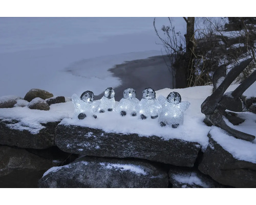 Figurines décoratives de pingouins avec éclairage sur un mur de pierre en hiver
