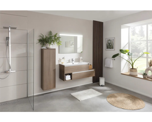 Helles Badezimmer mit Dusche, Waschtisch mit Spiegel, Hochschrank und dekorativen Elementen.