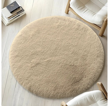 Runder, beiger Teppich auf hellem Holzboden, umgeben von Stühlen und Büchern.