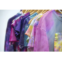 Mehrfarbige T-Shirts mit Batikmuster hängen auf einer Kleiderstange.