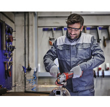 Mann arbeitet mit einem Winkelschleifer an Metall.