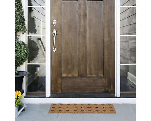 Fussmatte mit Willkommensgruss vor einer Haustür