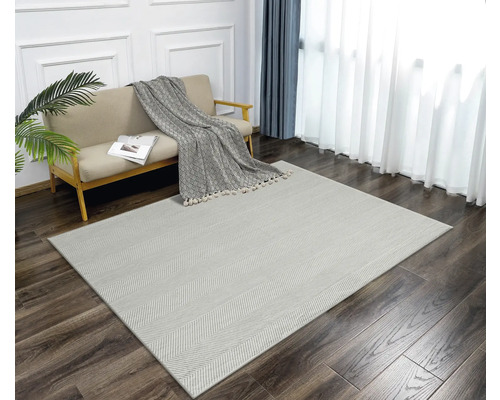 Salon avec canapé et tapis à chevrons sur parquet