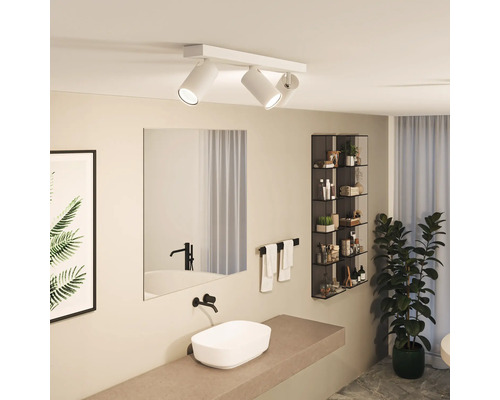 Salle de bain avec plafonnier à trois spots, miroir, lavabo et décoration