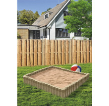 Bac à sable avec bordure en bois dans le jardin devant une maison