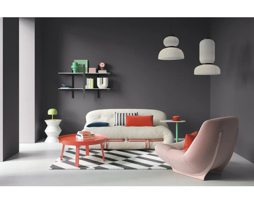 Wohnzimmer mit Sofa, Sessel, Teppich, Tisch und Regalen