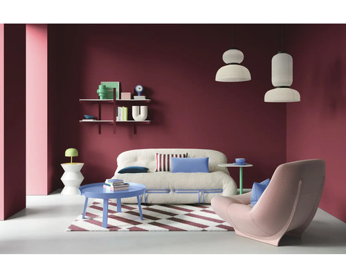 Wohnzimmer mit Sofa, Sessel, Couchtisch und Regalen an einer farbigen Wand