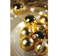 Boules de Noël décoratives dorées sur une assiette avec guirlande lumineuse