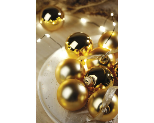 Boules de Noël décoratives dorées sur une assiette avec guirlande lumineuse