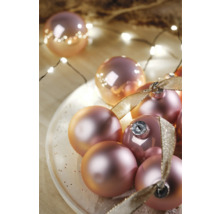 Boules de Noël décoratives avec ruban sur une assiette et guirlande lumineuse