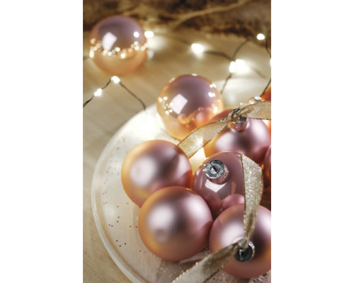 Boules de Noël décoratives avec ruban sur une assiette et guirlande lumineuse