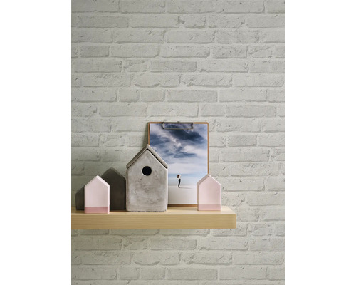 Wand mit Backsteintapete, Holzregal mit Hausdekorationen und Bild auf einem Klemmbrett