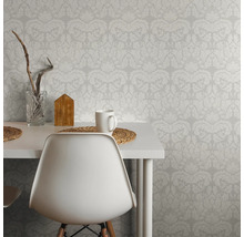 Scène avec papier peint à motifs, table, chaise, tasse et décoration, qui montre une ambiance lumineuse et organisée
