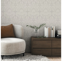 Vue d'une pièce avec papier peint à motifs floraux, fauteuil et commode