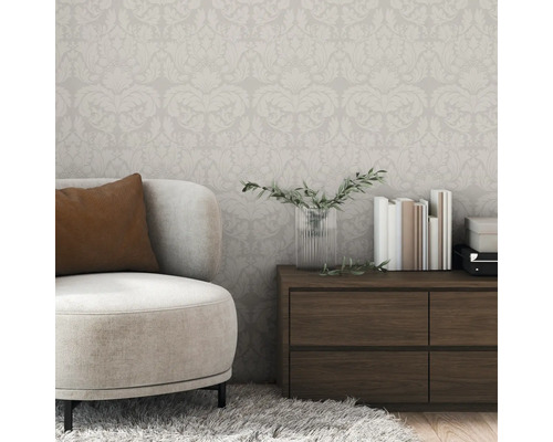 Raumansicht mit floral gemusterter Tapete, Sessel und Kommode