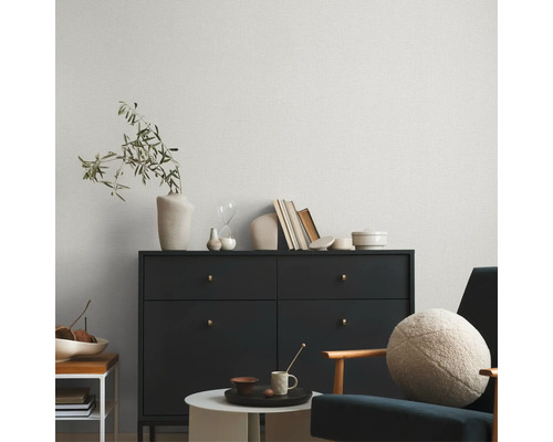 Wohnzimmer mit Kommode, Sessel und gemusterter Tapete