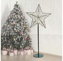 Dekorativer Leuchtstern auf Ständer neben Weihnachtsbaum und Geschenken