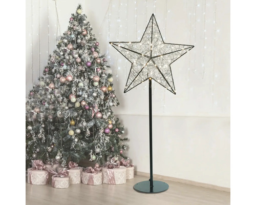 Dekorativer Leuchtstern auf Ständer neben Weihnachtsbaum und Geschenken