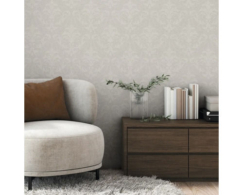 Wohnzimmer mit beigem Sessel, Holzkommode und gemusterter Tapete