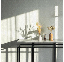 Arrangement décoratif avec des fleurs séchées sur une console devant un mur à motifs.