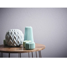 Vases décoratifs sur une table en bois devant un papier peint à motifs