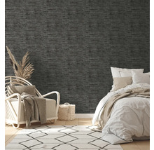 Schlafzimmer mit grauer Struktur-Tapete, Bett, Sessel und Teppich