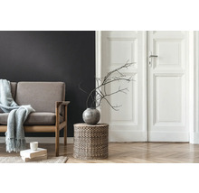 Salon avec canapé, table d'appoint en osier tressé, vase avec des branches et parquet