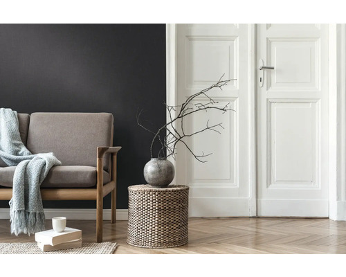 Salon avec canapé, table d'appoint en osier tressé, vase avec des branches et parquet