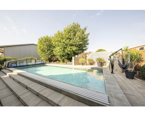 Piscine extérieure avec couverture, escalier et support de hamac dans le jardin