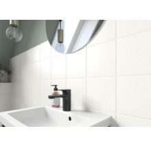 Lavabo de salle de bain avec robinet, distributeur de savon et miroir devant un mur carrelé