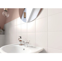 Salle de bain lumineuse avec lavabo, robinet et carreaux muraux carrés
