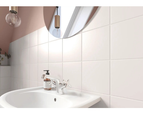 Salle de bain lumineuse avec lavabo, robinet et carreaux muraux carrés