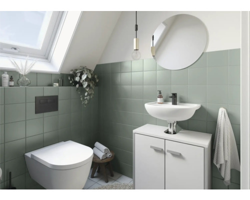 Salle de bain avec fenêtre de toit, toilettes, lavabo, miroir et carreaux verts
