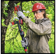 Eine Frau mit Schutzhelm und Schutzbrille benutzt eine Akku-Astschere für die Gartenarbeit.