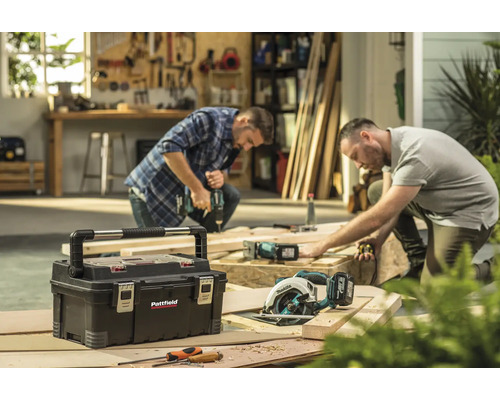 Werkstattszene mit Werkzeugkasten, Handkreissäge und zwei Handwerkern bei der Arbeit