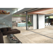 Heller Wohnraum mit Fliesenboden, Sofa, Tisch und Küchenbereich.