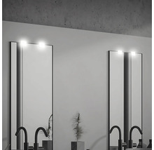 Zwei beleuchtete Spiegel mit Armaturen in einem Badezimmer.