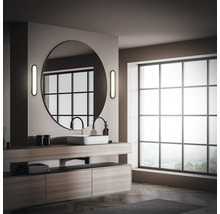 Badezimmer mit Waschtisch, rundem Spiegel und großem Fenster