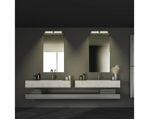 Salle de bain avec deux lavabos, miroirs, serviettes et étagères dans des tons foncés.