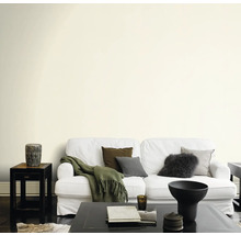 Salon avec canapé, table et éléments décoratifs devant un mur peint.