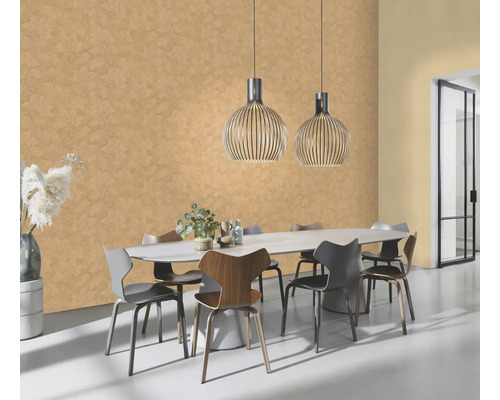 Salle à manger avec table ovale, chaises et suspensions devant un mur avec papier peint à motifs