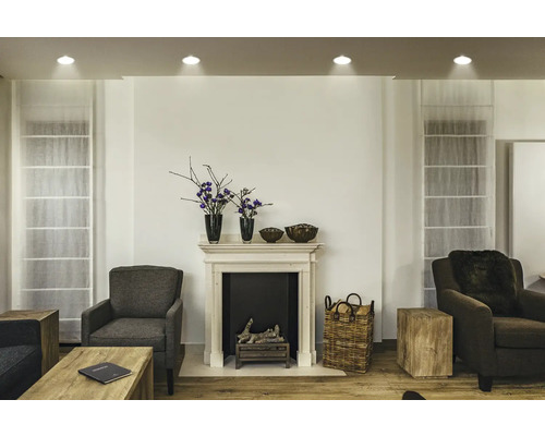 Wohnzimmer mit Kamin, Sesseln und Holzbeistelltischen.