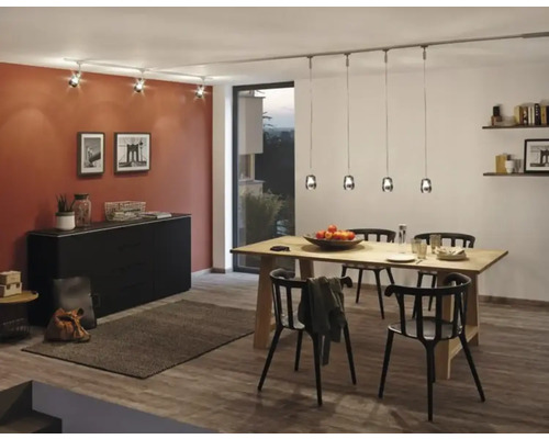Salle à manger avec table en bois, chaises noires, commode et système d'éclairage