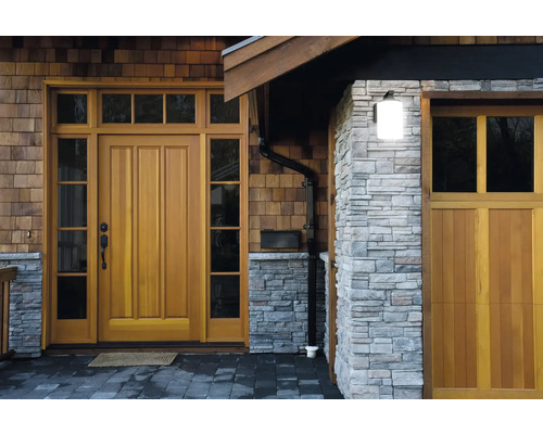 Extérieur d'une maison avec porte en bois, mur en pierre et gouttière